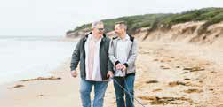Same sex couple walking their two dogs along a beach