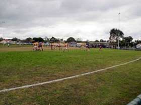 Young Australian Rules footballers training on a football oval