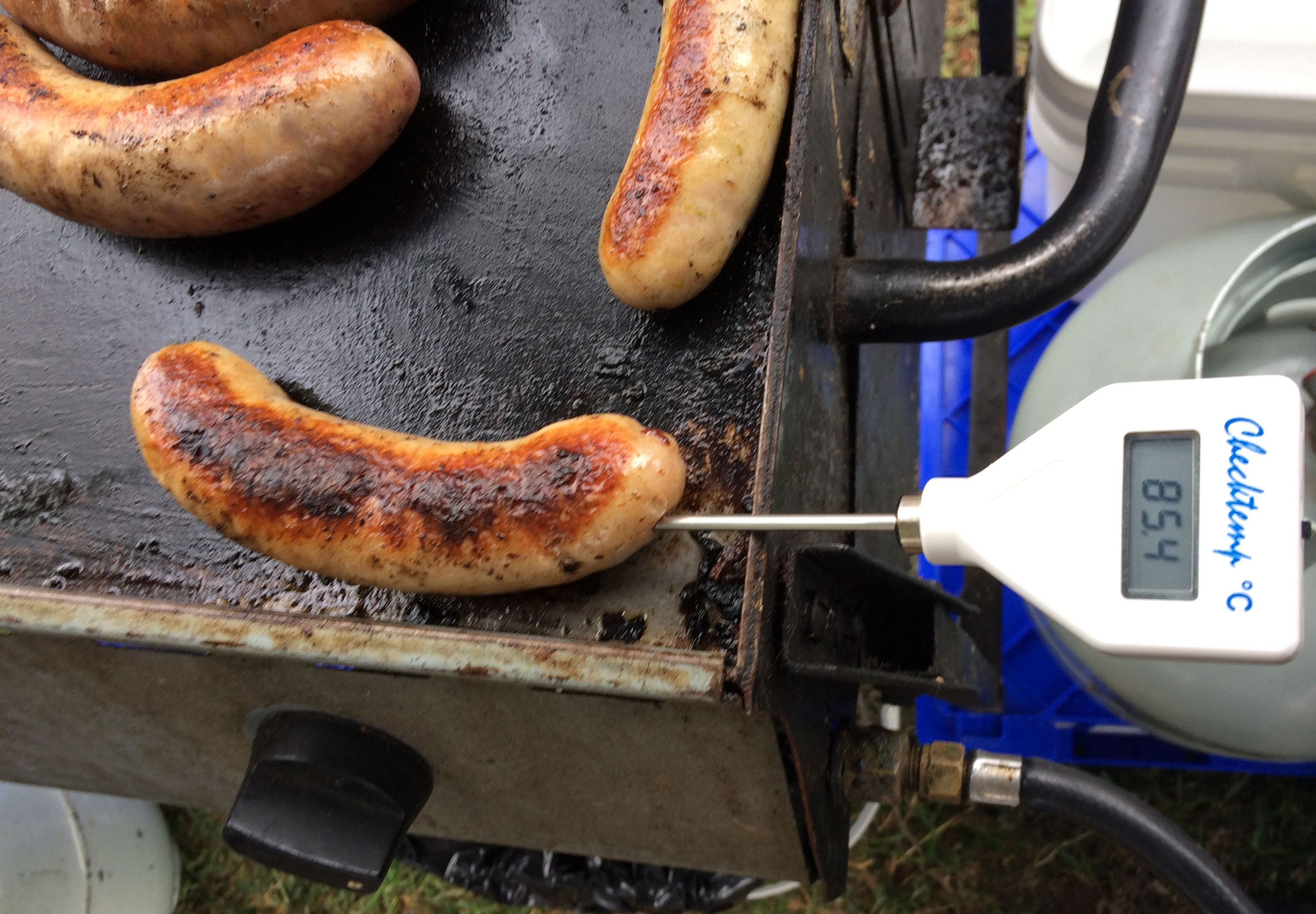 Close up image of food thermometer showing temperature of 78.6 degrees celsius while cooking sausages