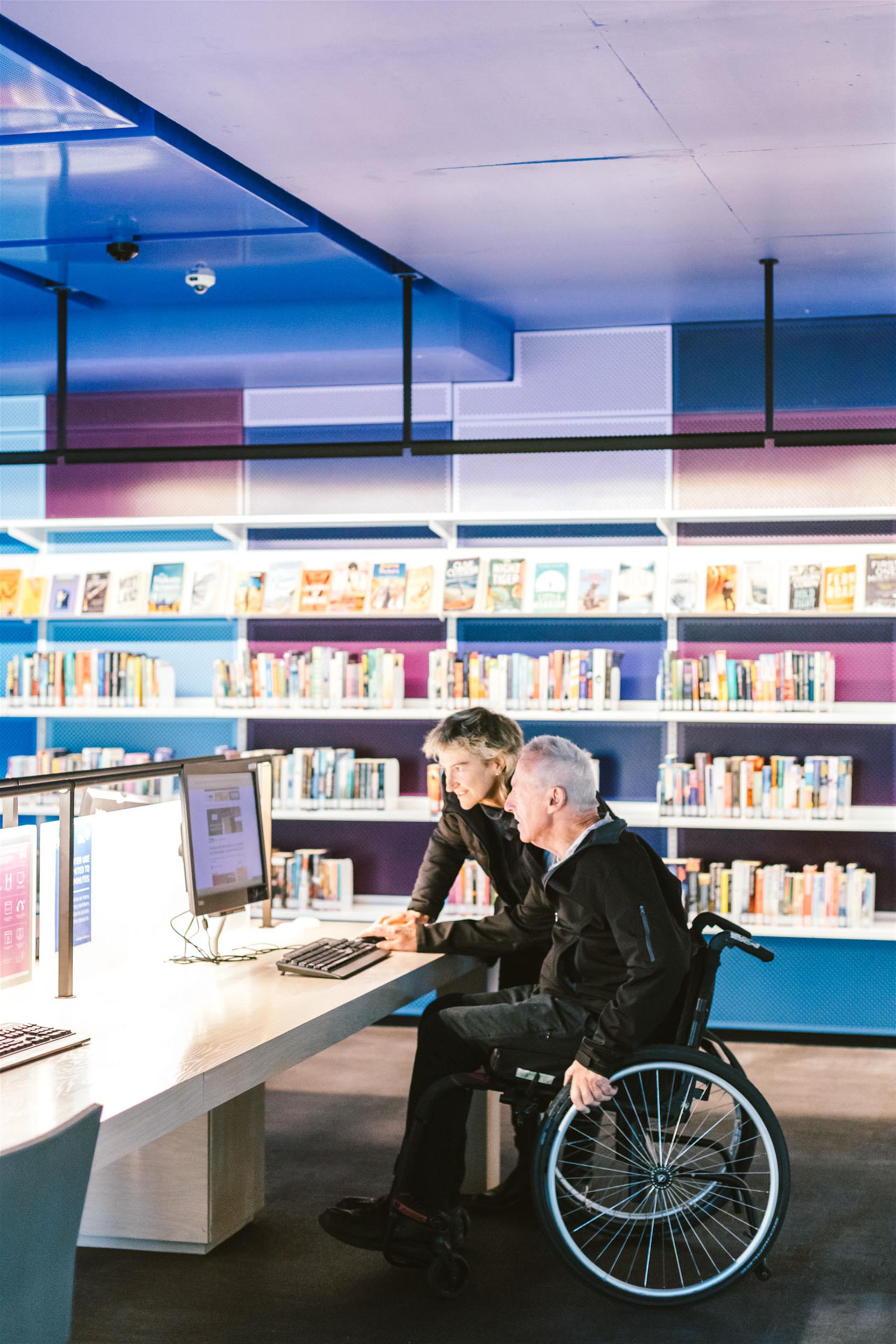 Two people looking at a computer in the library.