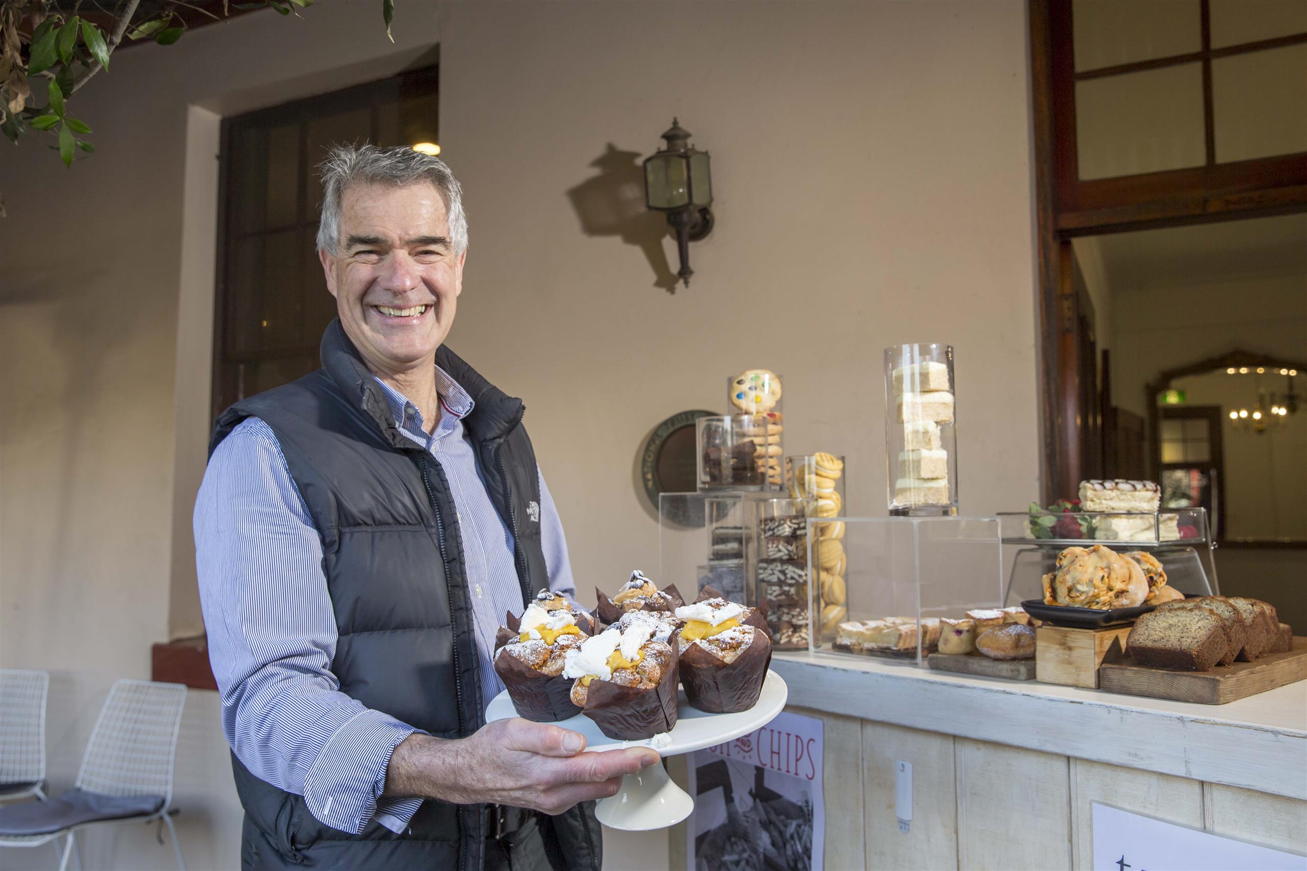Cafe owner holding a tray of muffins