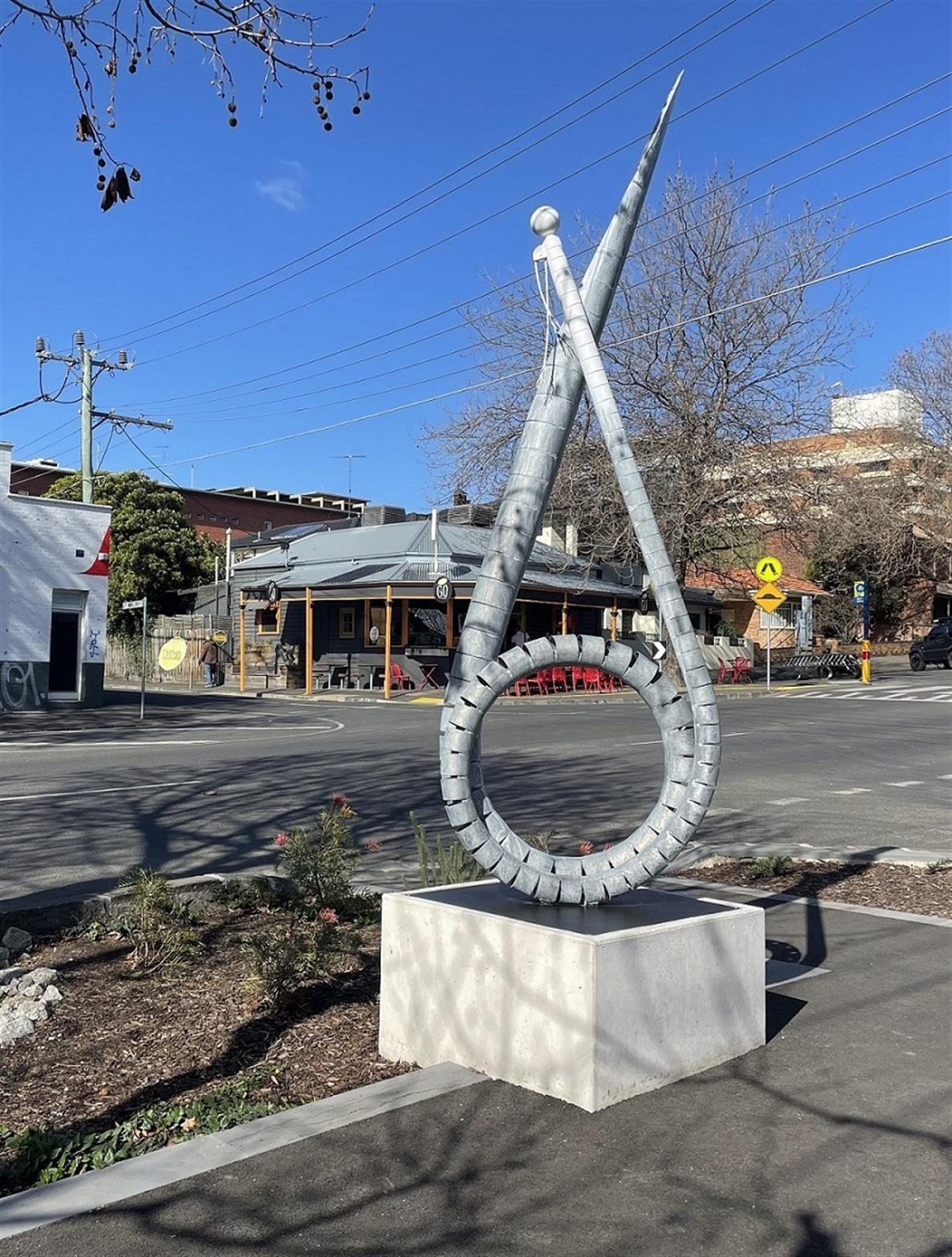 Public art sculpture metal pole on concrete slab