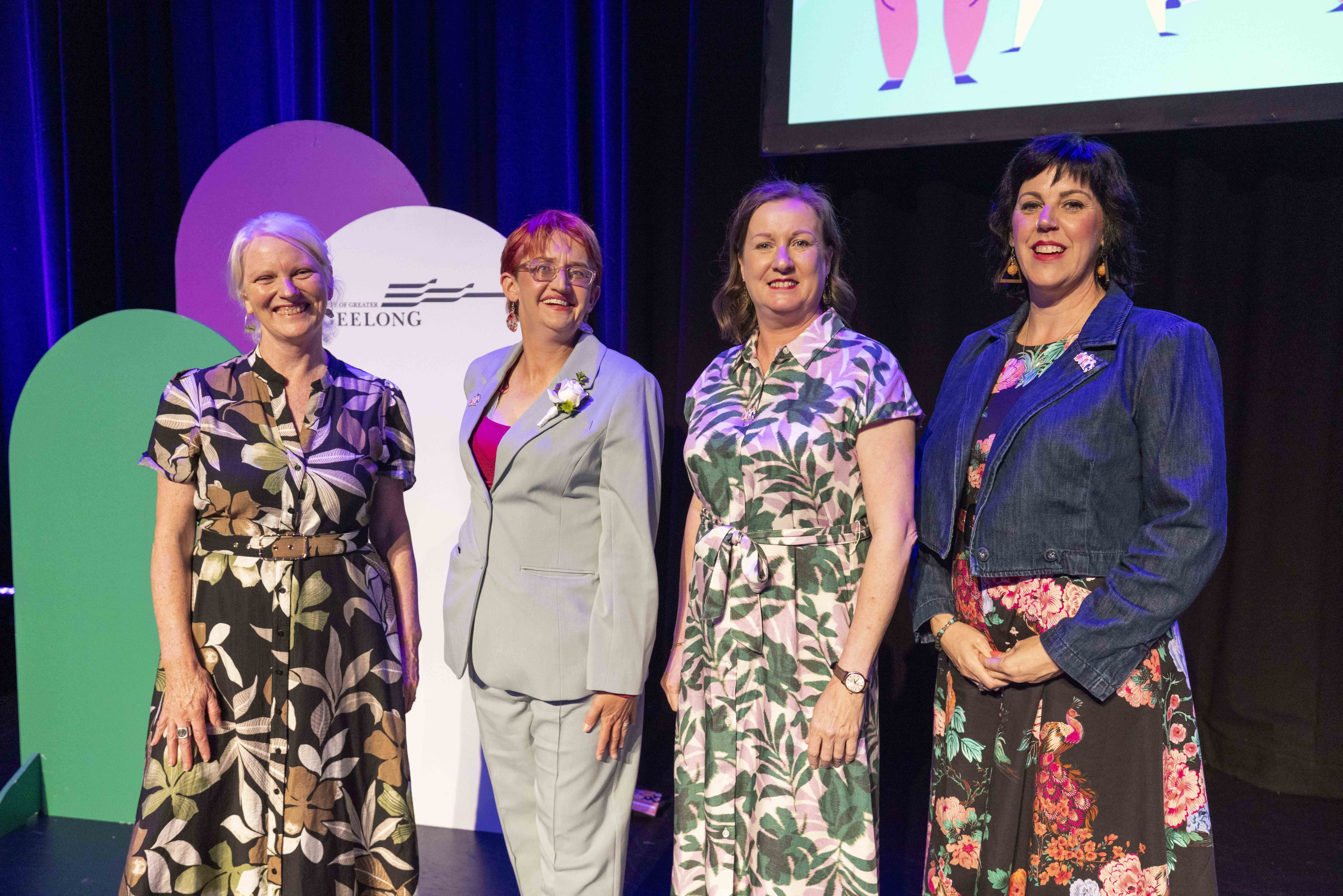 Four women standing and smiling