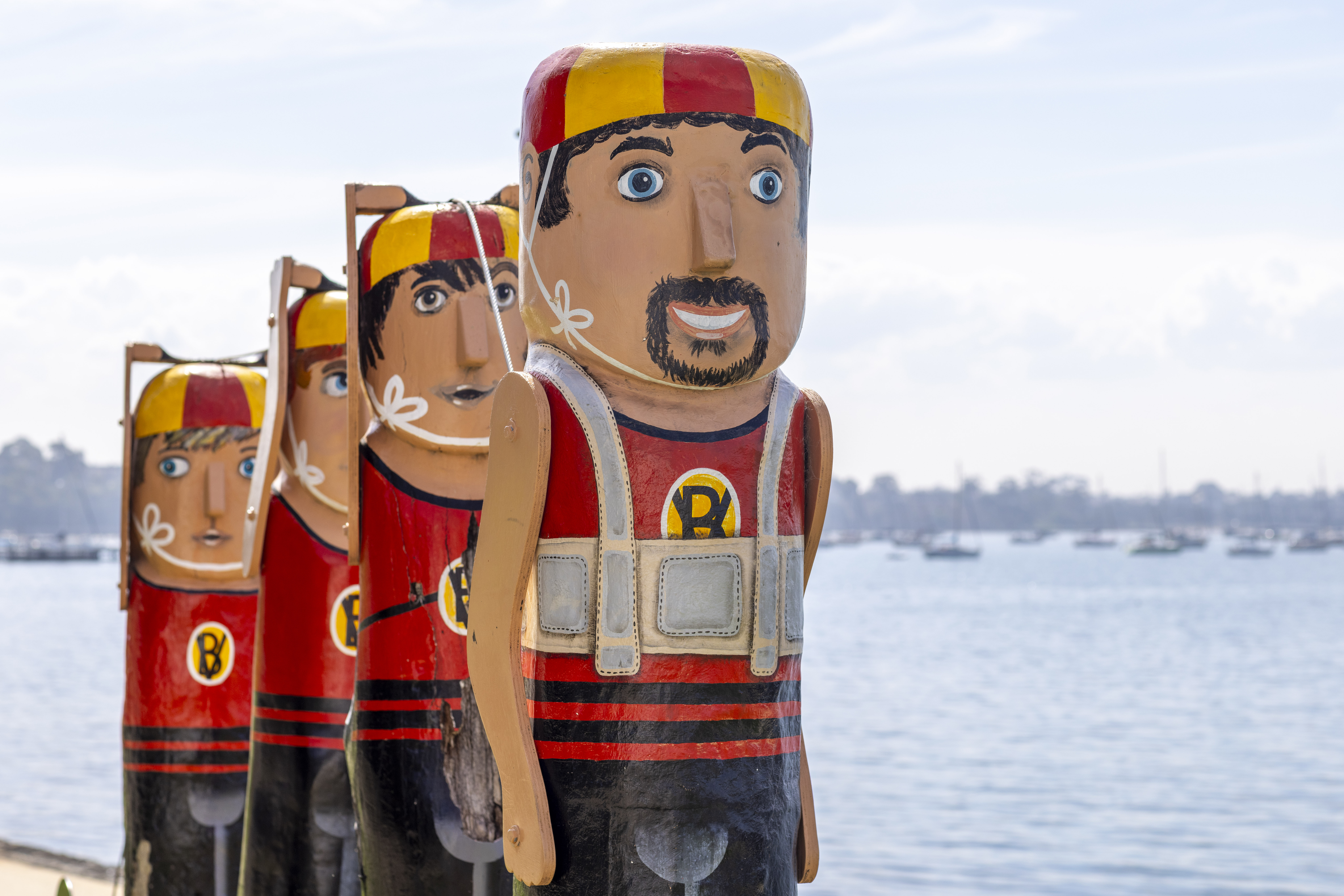 Four painted bollards dressed in red and black bathing suits and red and yellow swim caps