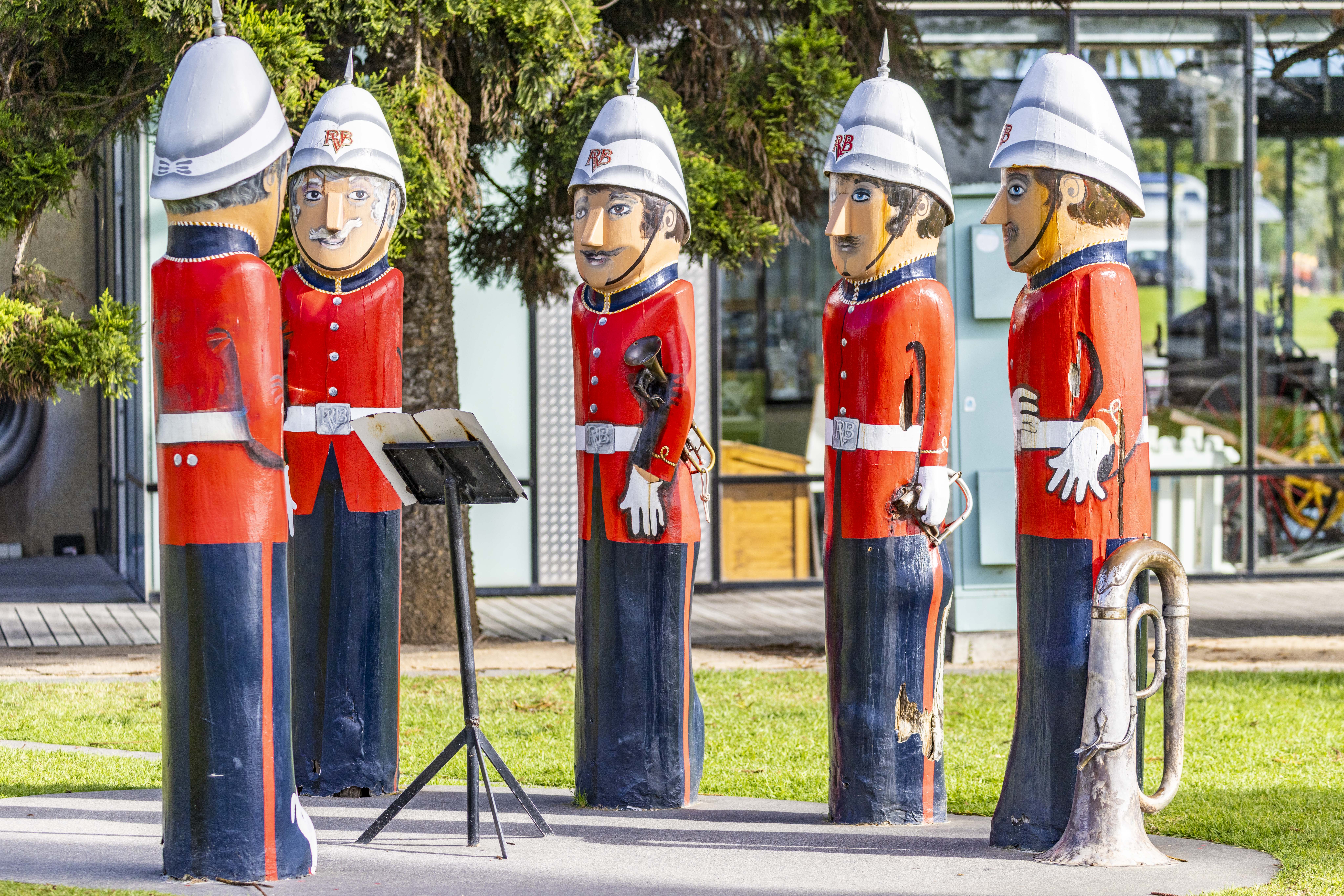Five painted bollards wearing military suits combined of white hats, red coats and blue pants. One is conducting the other four who are holding instruments.