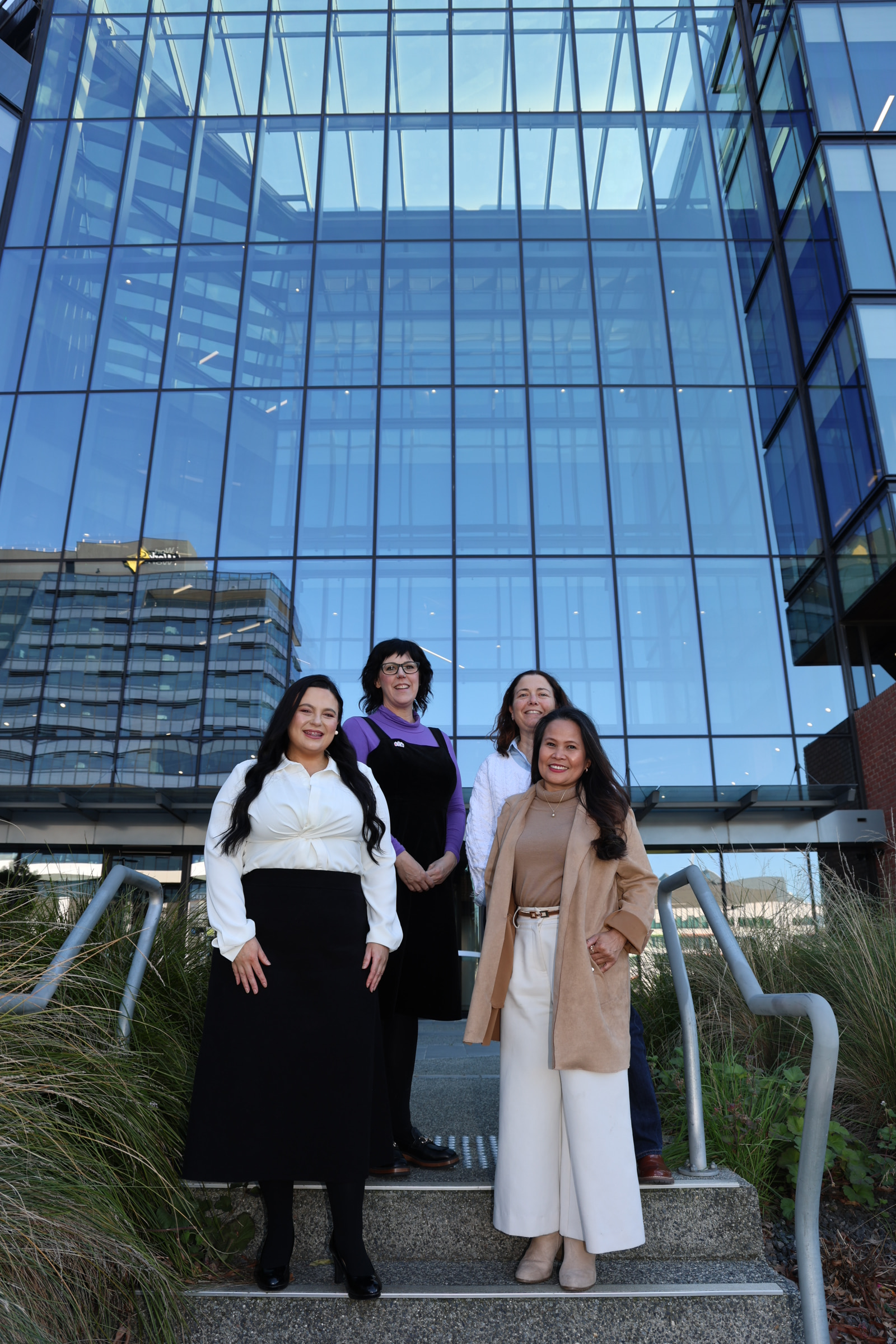 Four women standing in front of a building smiling.