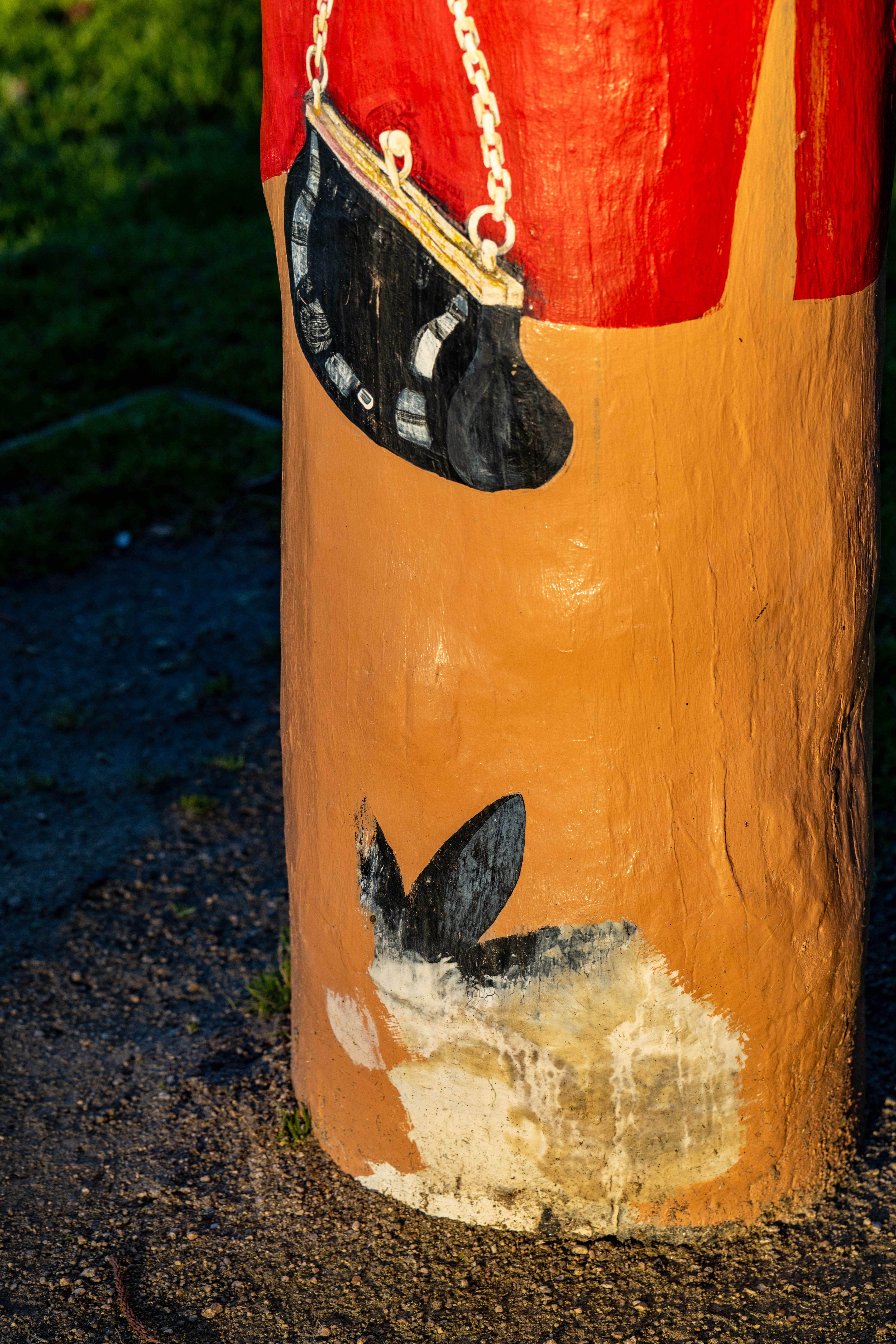 Grey and white rabbit at the base of a bollard