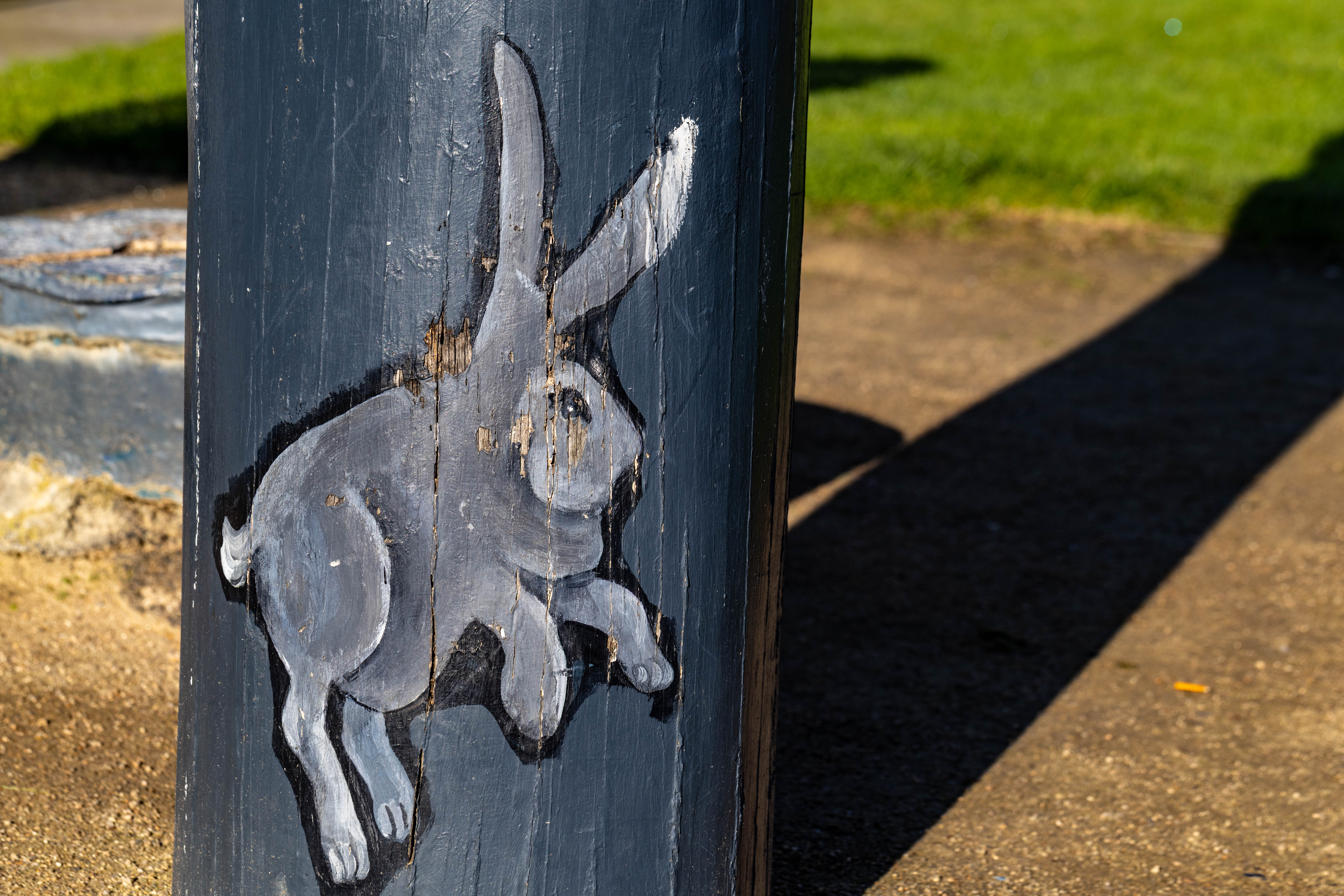 Grey rabbit at the base of a bollard