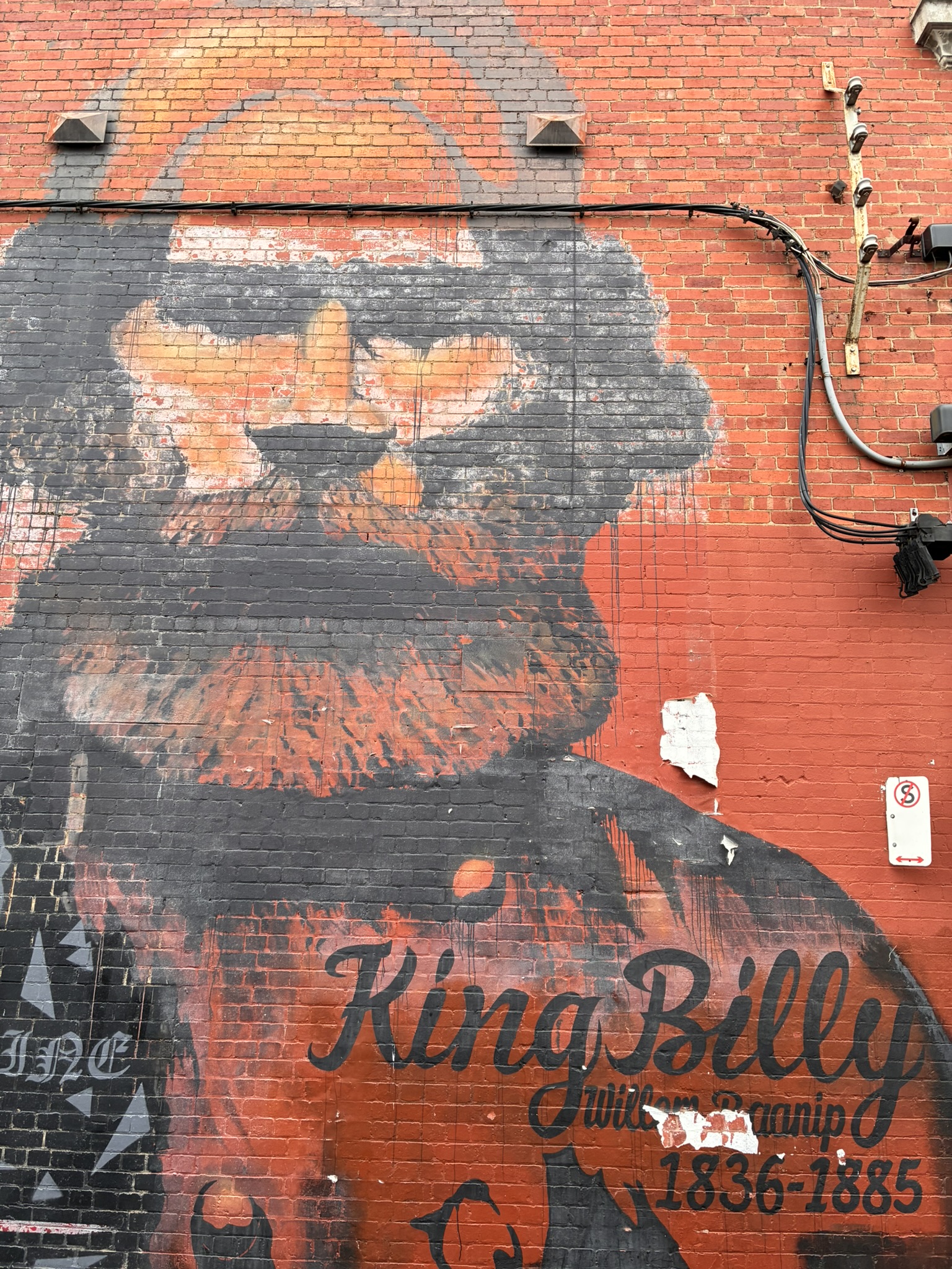 Large scale mural of local First Nations man. Black and white paint on red brick.