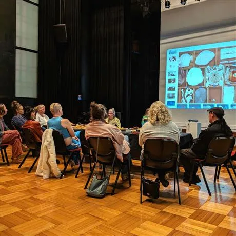 People sitting around tables watching a screen