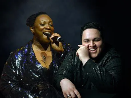 Image of lady singing and man seated