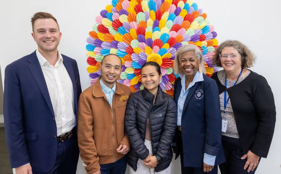 Cr Trent Sullivan and Cultura CEO Rebecca Smith (at rear) with program participants Kio Ner Moo Sanhtwe and Nanah Yohel, and business mentor June O’Brien. Group of five people standing in front of a colourful mural