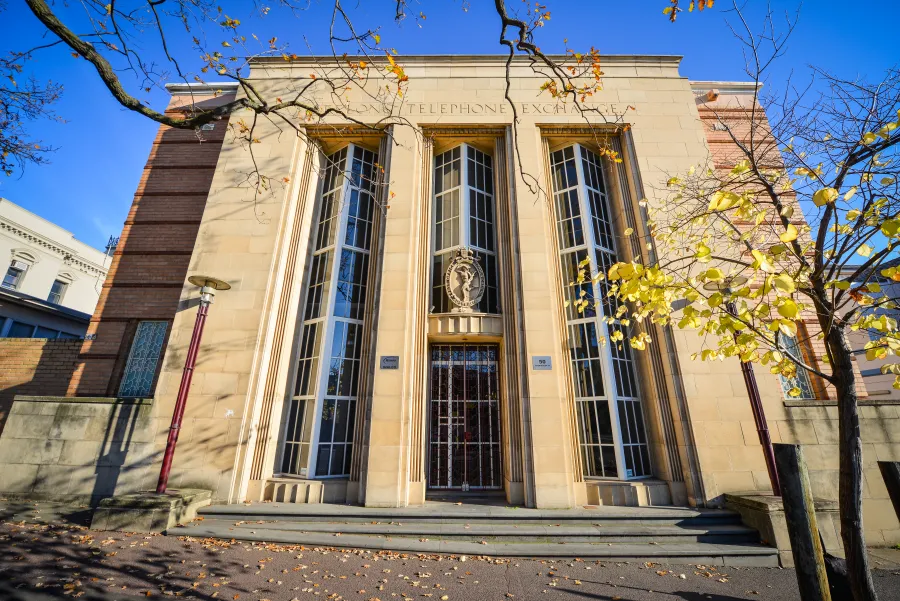 Telephone Exchange Historic yellow brick building with long narrow windows from ground to roof with ornate door topped with large decorative crest
