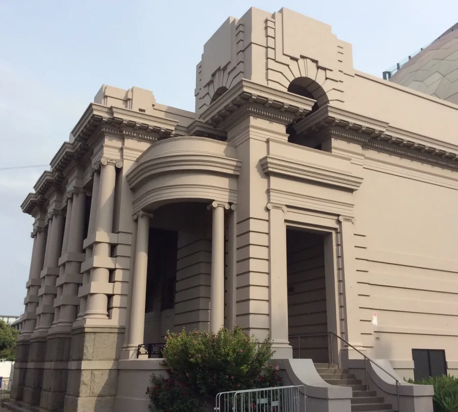 Beige heritage building with arches and columns sitting behind the Geelong Library