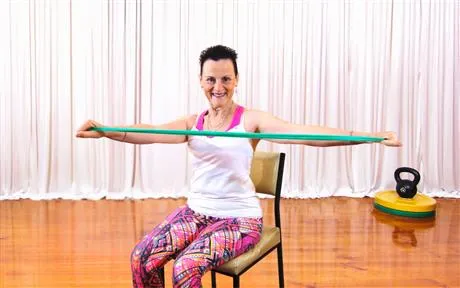 Image of lady sitting in chair stretching a band for strength