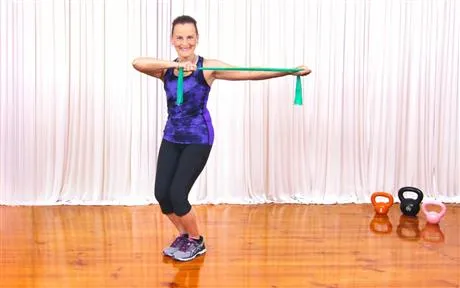 Image of lady standing and stretching band for strength