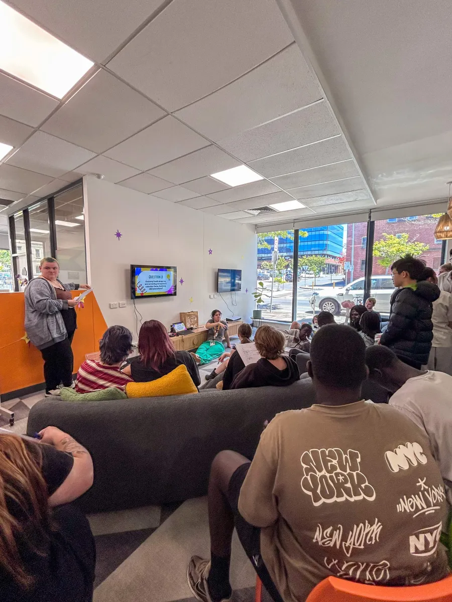 Young people standing and sitting, listening to a speaker
