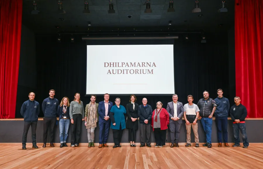 Group photo of people in single line in front of stage