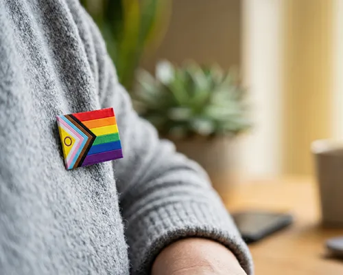 Supports for LGBTQIA+ communities person with pride badge on jumper