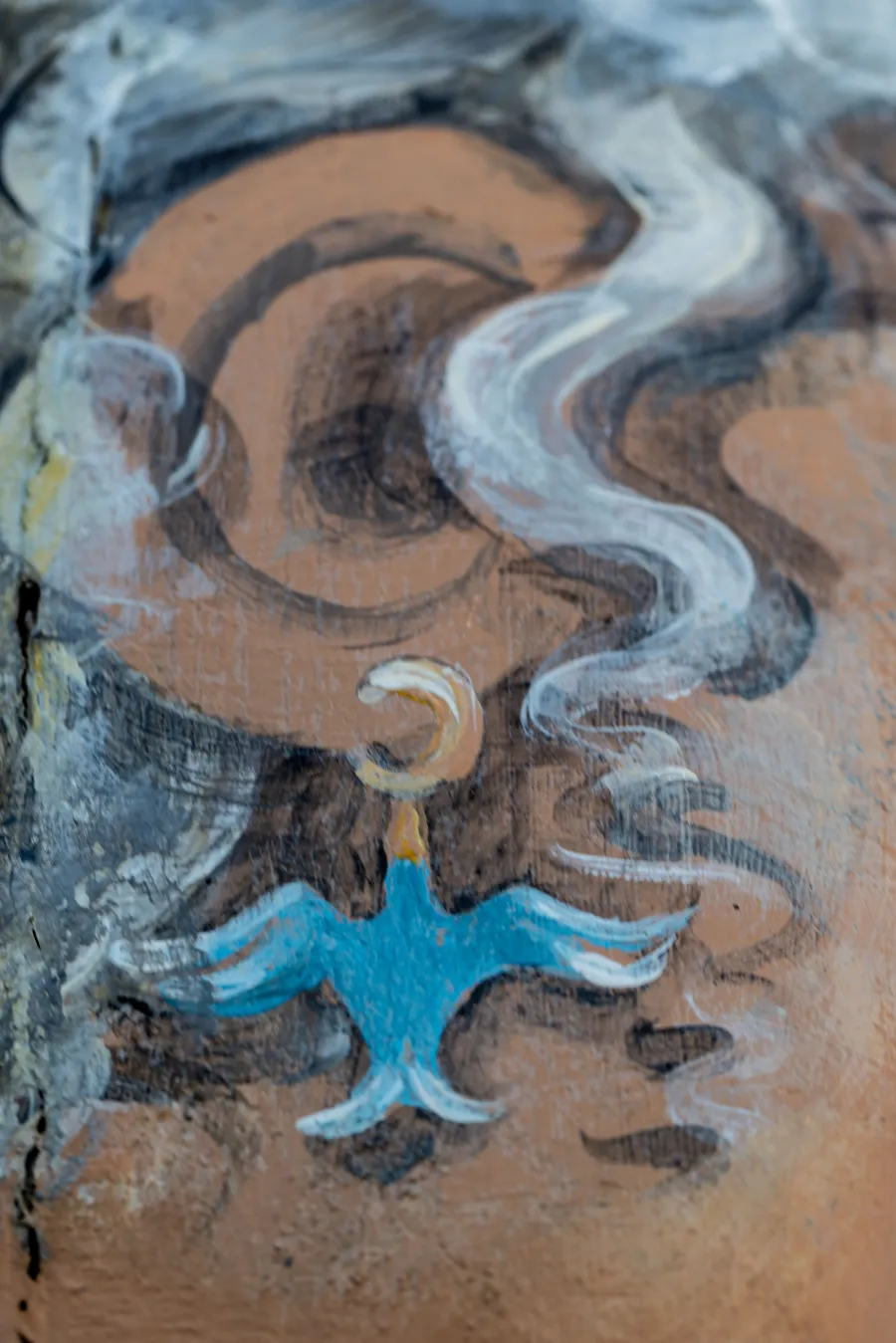 Painted earing of blue bird on bollard