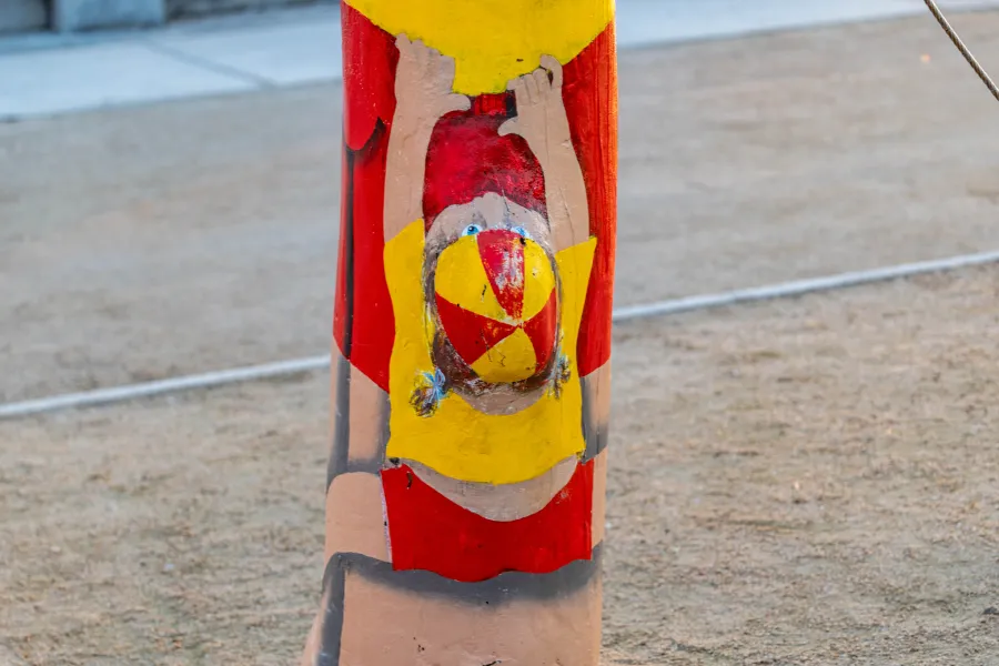 Painted image of small child haining from shorts of larger bollard