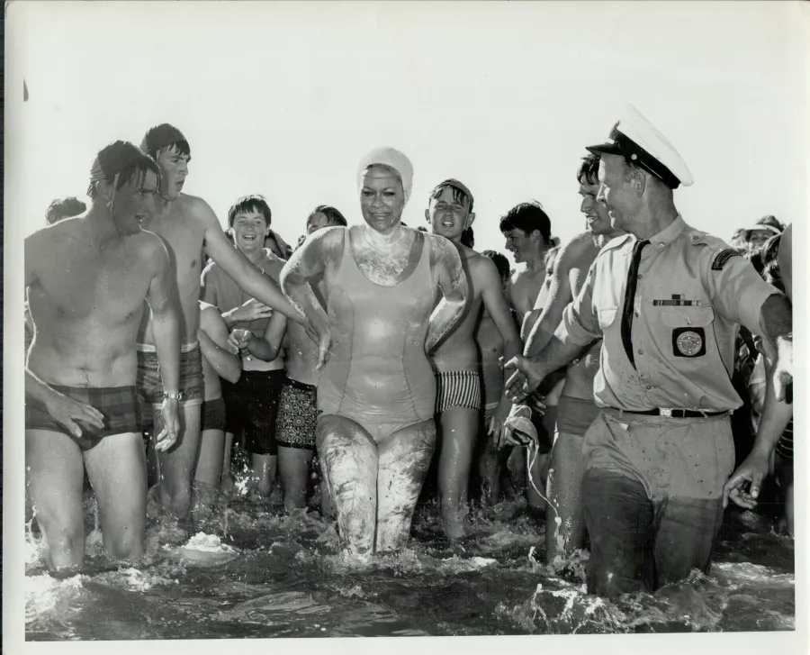 Woman standing in water surrounded by well wishers
