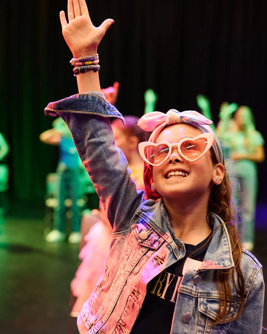 Geelong Wonder Children's Festival A young girl smiling, wearing love heart glasses and raising one hand in the air