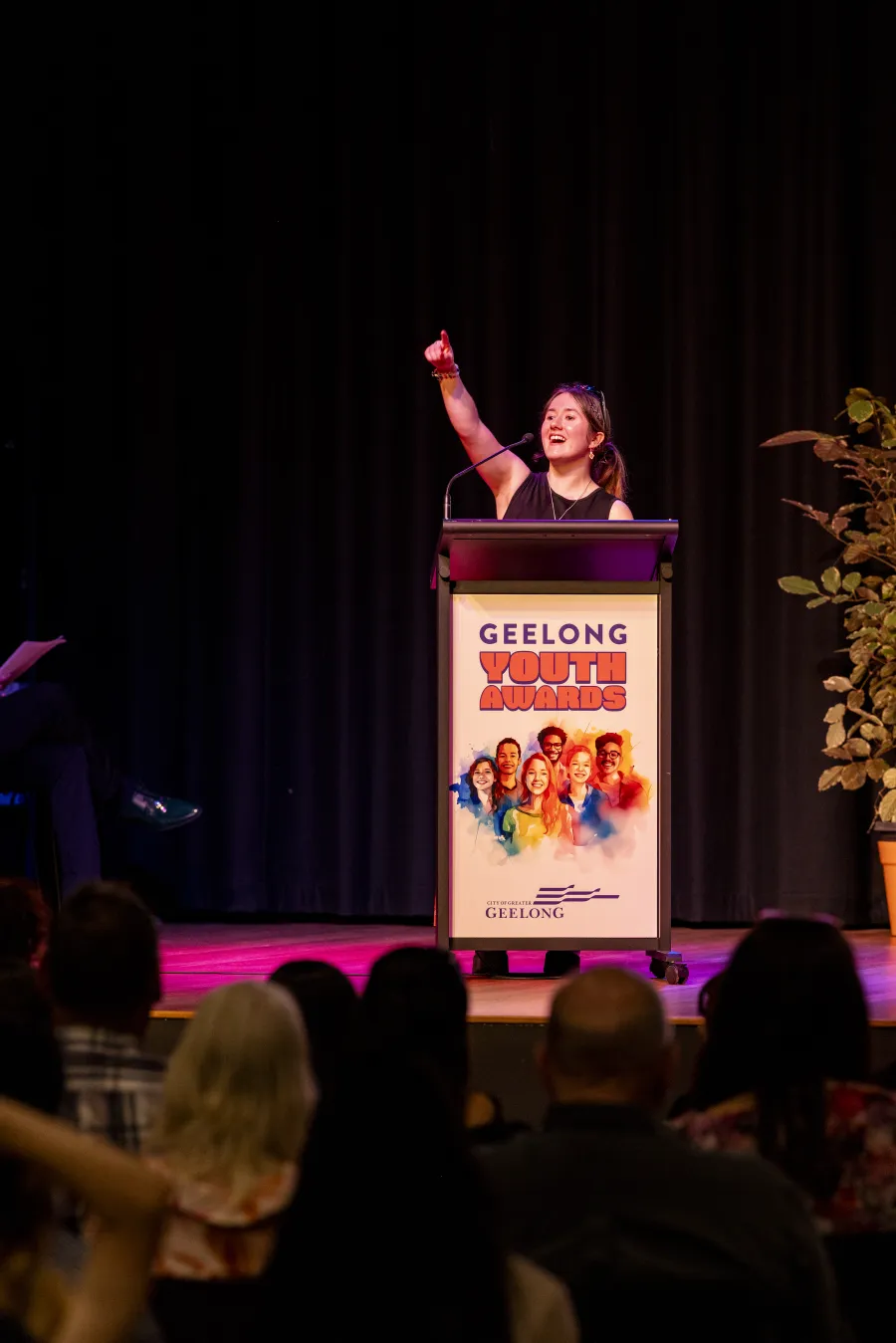 Young person on stage pointing.