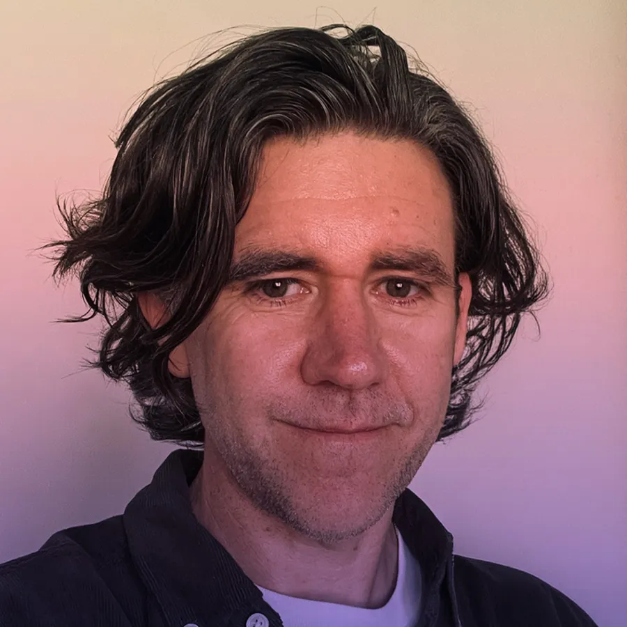 Ben Bjork Portrait photo of man with brown hair standing in front of gradient background