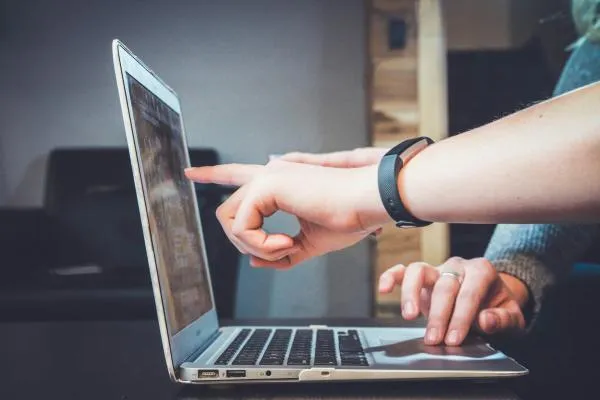 person pointing at a laptop screen