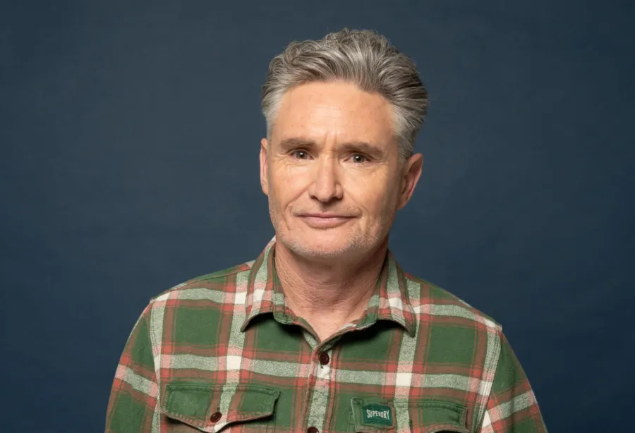 Dave Hughes Dave Hughes posing in front of dark blue wall.