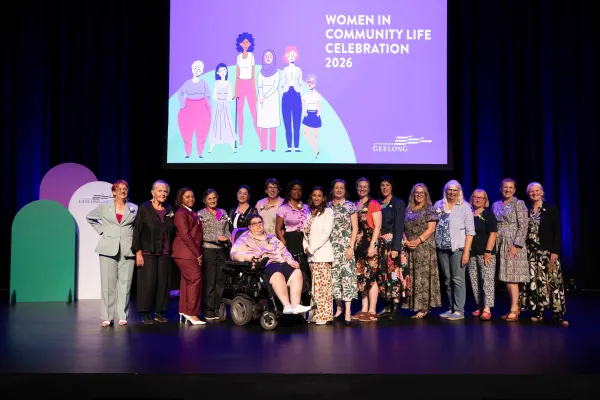 A group of women standing or sitting in a wheelchair in a line on stage