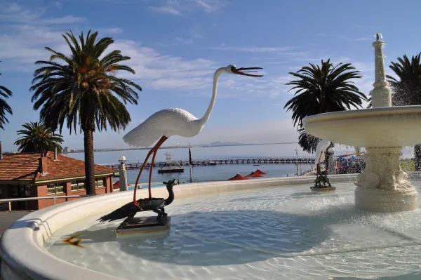 Eastern Beach Baths Art Deco fountain with statues of turtle and crane set against bath house building and palm trees