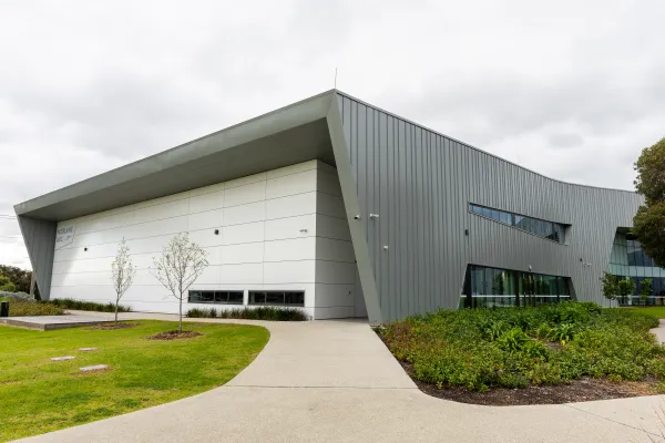 Outside view of auditorium building with white walls and curved grey roof.