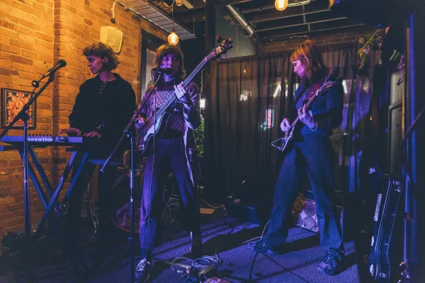 Image of three band members playing a gig. One playing keyboard, one guitar and one bass.