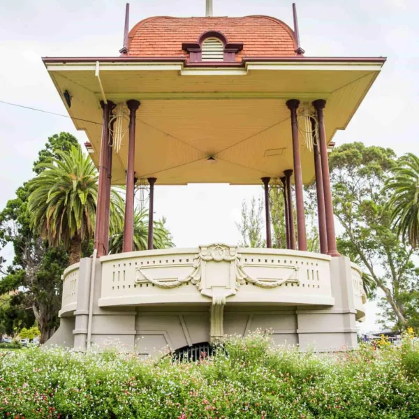 Hitchcock Memorial Bandstand Heritage listed rotunda with red roof surrounded by green bushes and trees.