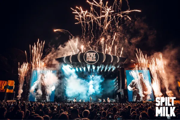 Outdoor stage with fireworks and a big crowd of people