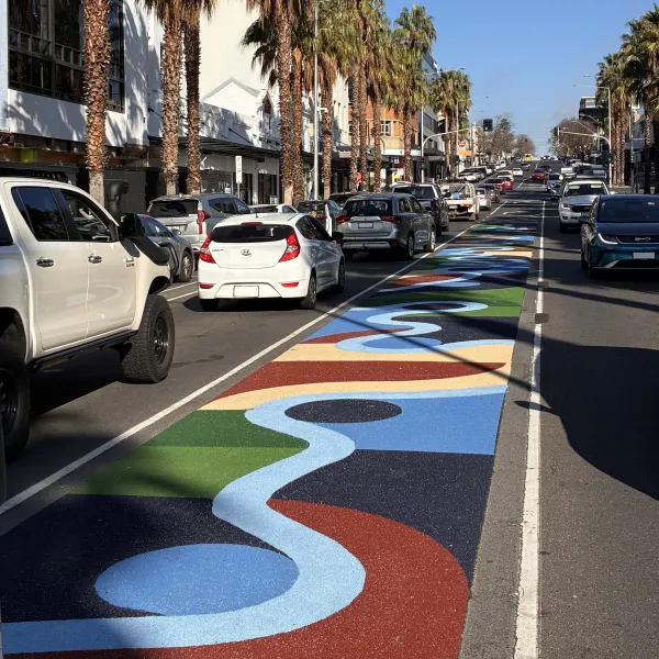 Colourful large scale public artwork located in the middle of a street made from recycled glass