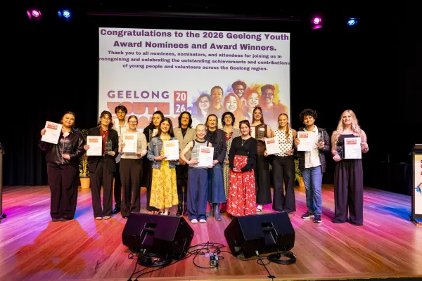 Young people and adults standing on a stage smiling.