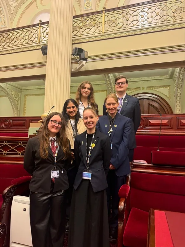 six young people standing in to columns of three dressed in their formal wear at Parliament