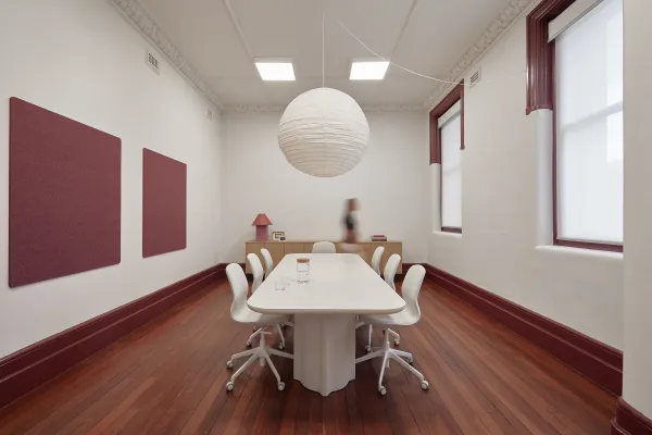 Burgundy coloured co maker space with large white table and chairs