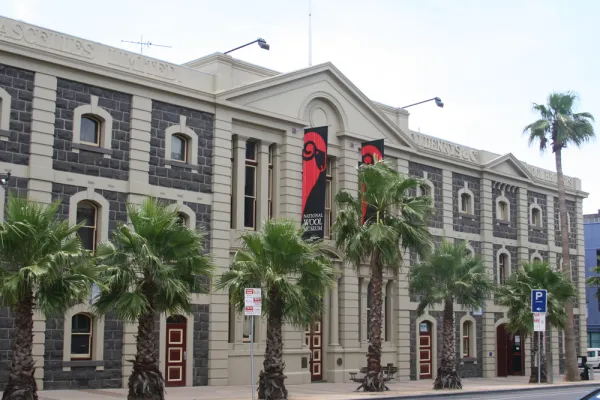 Large heritage listed building with palm trees out front.