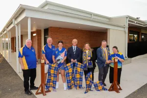 North Shore FNC rep Paul Brady, President Maryian Szponar, Vice President & Netball Operations Lead Edwina Wilkens, Mayor Kontelj, Ella George MP, Cr Aitken and Vice President Tamara Wills People standing in front of new building and cutting a ribbon made of footy scraves