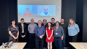 LGBTQIA+ Advisory Committee meeting Group of people in person and online smiling