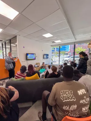 Young people standing and sitting, listening to a speaker