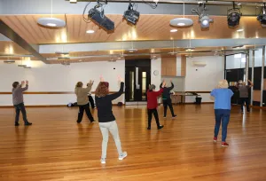 A group of people moving at Tai Chi class.