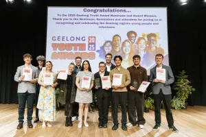 Young people standing on a stage holding certificates and smiling
