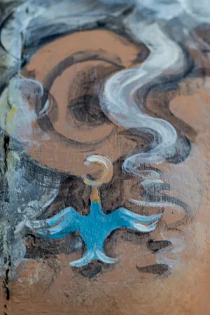 Painted earing of blue bird on bollard