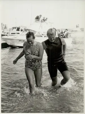 Woman walking out of water alongside a man