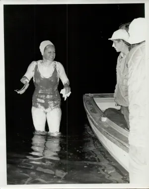 Woman standing in water next to people in boat
